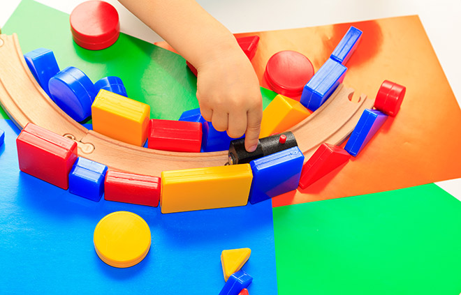 A child playing trains on blocks and train tracks